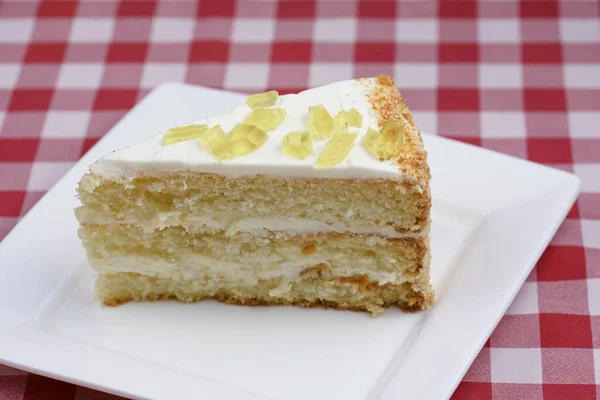 赤いテーブルクロスの上に白いプレートにクリームとレモンスポンジケーキの作品。イタリアの概念. — ストック写真