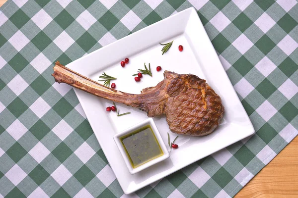 Nahaufnahme der einzelnen gegrillten Rippenspitze mit Rosmarin, Salz, Kräutern und Granatapfelkernen. Tomahawk-Steak. — Stockfoto