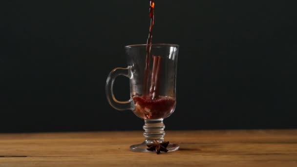 Warme glühwein wordt gegoten in een Iers koffieglas op een houten tafel op zwarte achtergrond. — Stockvideo