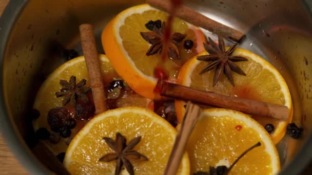 Wine is poured from wine bottle into pan with orange pieces, cinnamon and star anise. — Stock Video