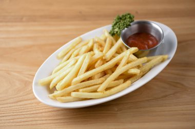 Altın patates kızartması yenmeye hazır. Kırsal ahşap arka planda beyaz domates sosuyla servis ediliyor..