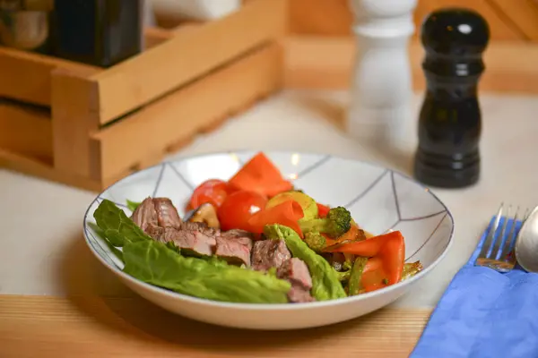 Salada com carne e legumes. Cozinha italiana, pratos diferentes servidos no restaurante na mesa de madeira rústica leve . — Fotografia de Stock