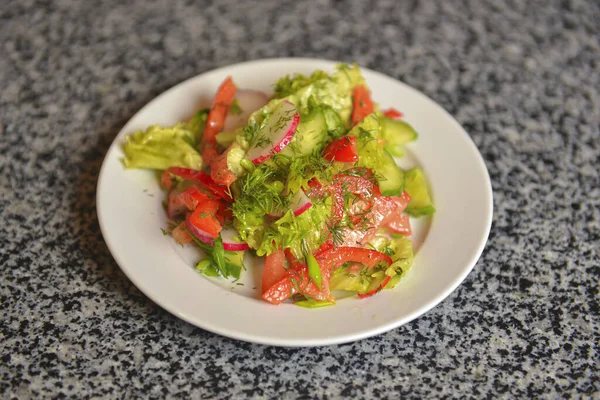 Salada de legumes com rabanetes, pepino, pimentão doce e endro. Servido em uma placa branca sobre mesa texturizada cinza . — Fotografia de Stock