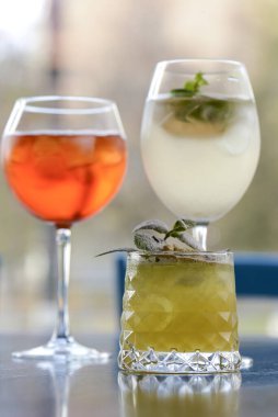 Koyu renkli ahşap bir masada servis edilen üç renkli ferahlatıcı kokteyl ve bulanık arka plan..