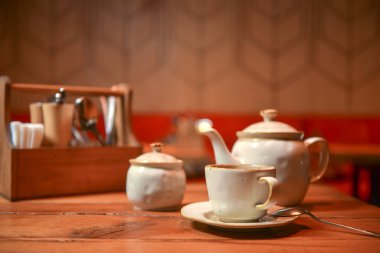 Restorandaki ahşap bir masada servis edilen beyaz çay seti. Çay zamanı. Seramik çay seti. Konsepti tüketiyorum.