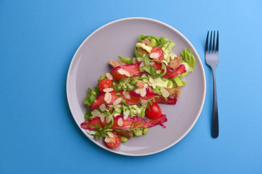 Taze salata, füme tuzlu somon, domates ve kabak çekirdeği. Gri dokuda gri bir tabakta servis edilir..
