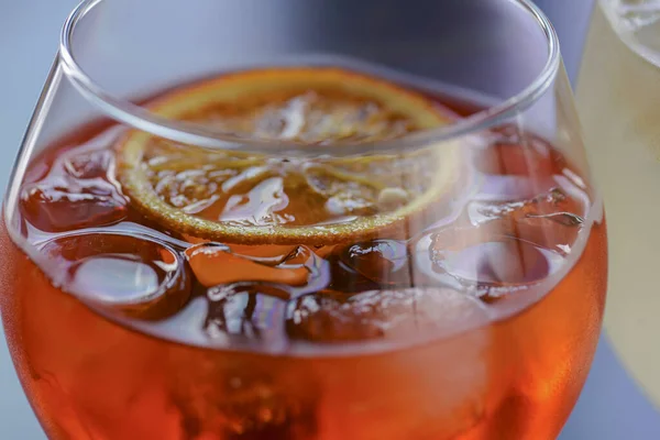 Cóctel de alcohol frío de verano con hielo y naranja en una copa de vino y paja de plástico negro sobre fondo claro y borroso —  Fotos de Stock