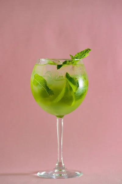 Mojito alcohol cocktail, tropische drank met ijs, munt en limoen op pastelroze achtergrond met kopieerruimte. — Stockfoto