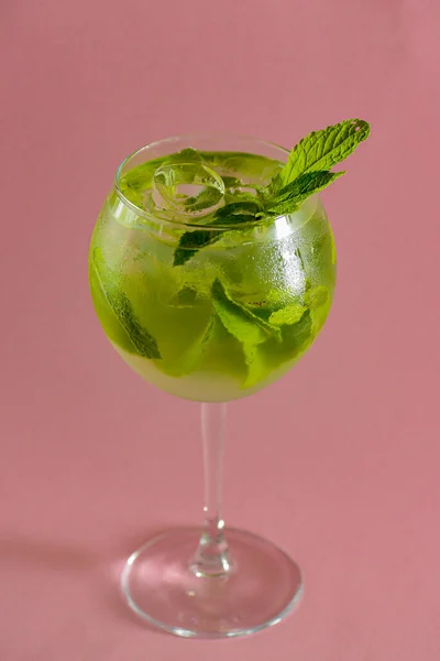 Cóctel de alcohol Mojito, bebida tropical con hielo, menta y lima sobre fondo rosa pastel con espacio para copiar . — Foto de Stock