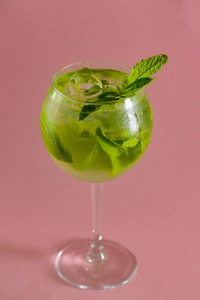 Coquetel de álcool Mojito, bebida tropical com gelo, hortelã e limão em fundo rosa pastel com espaço de cópia . — Fotografia de Stock