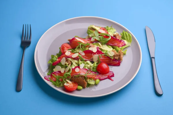 Fresh salad with smoked salted salmon, tomatoes and pumpkin seeds. Served on a gray plate over gray texture background. — Stock Photo, Image