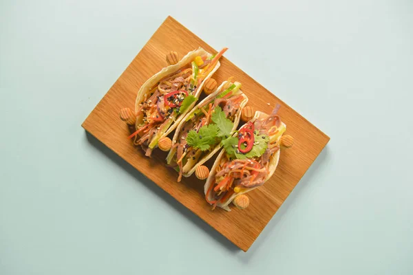 Auténticos tacos mexicanos de pollo y ternera. Tres tacos servidos en una tabla de madera sobre fondo de menta azul pastel . —  Fotos de Stock