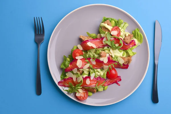 Salada fresca com salmão salgado defumado, tomates e sementes de abóbora. Servido em uma placa cinza sobre fundo textura cinza . — Fotografia de Stock