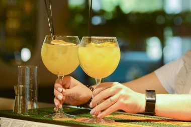 Garson bir barda, kafede ya da restoranda plastik pipetle iki bardak sarı alkollü içecek servis ediyor. Barmen iş başında..