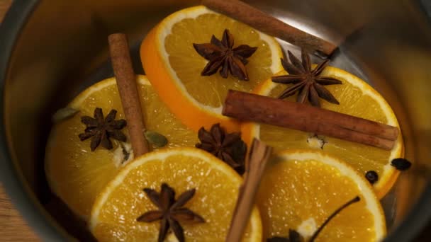 Olika kryddor faller i en kastrull med orangea bitar, kanel och stjärnanis. — Stockvideo