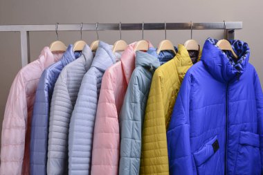 Marketteki askılarda asılı yeni ceket koleksiyonu. Modern baharın renkli arka planı, sonbahar dış giysisi.