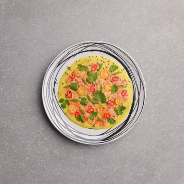 Somon balığı, domates, biber ve gri arkaplanda servis edilen taze yeşillik içeren soğuk salatalık avokado çorbası..