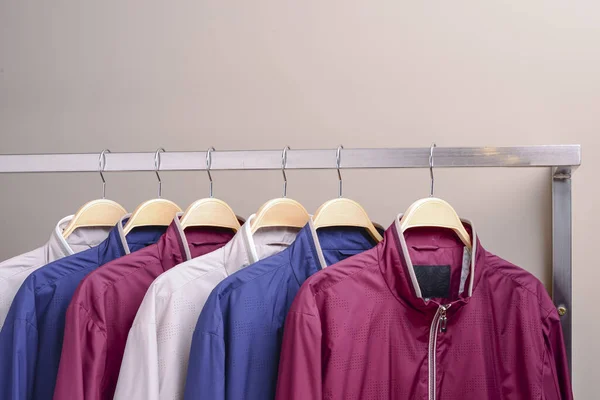 Riga di molte diverse giacche colorate con cappuccio, giacche sportive per uomini e donne. Abbigliamento stagionale in vendita . — Foto Stock