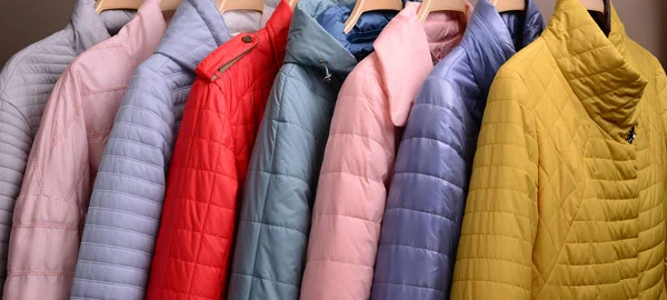 Marketteki askılarda asılı yeni ceket koleksiyonu. Modern baharın renkli arka planı, sonbahar dış giysisi.
