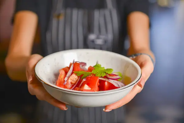 Close up de garçom servindo salada verde fresca com tomate e cebola. Empregado de uniforme no trabalho. Serviço de restaurante . — Fotografia de Stock