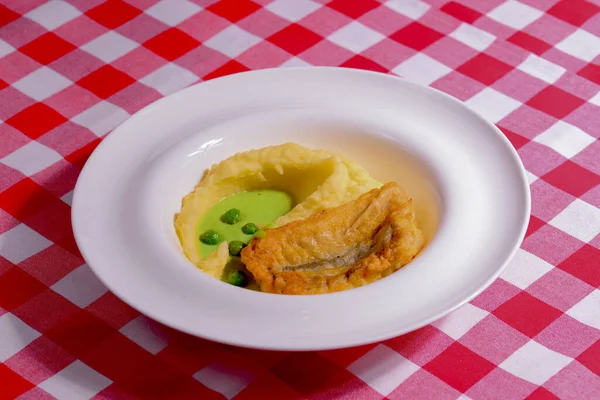 ปลาทอดกับมันฝรั่งบดและซอสเสิร์ฟบนจานสีขาวเหนือผ้าปูโต๊ะสีแดง . — ภาพถ่ายสต็อก