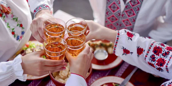 Ukrainian family in traditional closes has a dinner. Ukrainian culture. Family eating and clang glasses together. — Stock Photo, Image