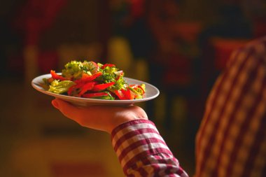 Garson sulu domatesli sebze salatası, marul, turp ve salatalık servis ediyor. Restoran servisi..