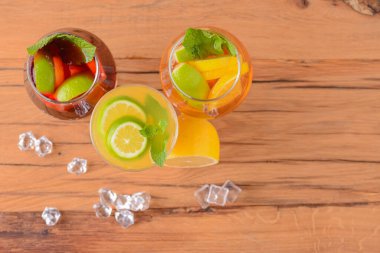 Limonlu, limonlu ve kırsal masada farklı bardaklarda servis edilen üç tropikal karışık içecek..