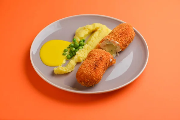 Κοτολέτες καραντίνας, τηγανητό κρέας σερβιρισμένο με πουρέ πατάτας και αρακά σε γκρι πιάτο πάνω από πορτοκαλί φόντο. — Φωτογραφία Αρχείου