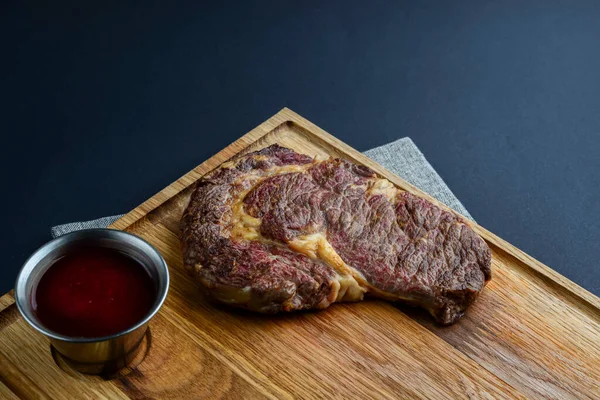 Bife de carne fresca e temperos em tábua de madeira rústica sobre fundo preto. Vista superior, flat lay, copiar banner espaço . — Fotografia de Stock