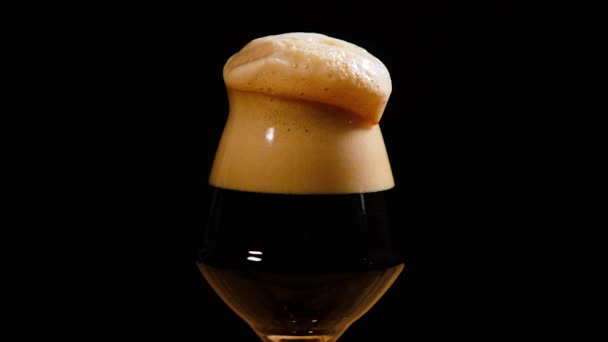 Mörk öl hälls i glas. Skum droppar från glaset. Kall öl i ett glas med vattendroppar — Stockvideo