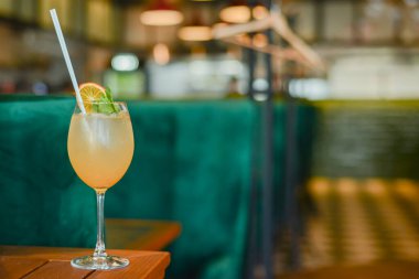 Buzlu ve portakallı soğuk yaz alkollü kokteyli ahşap masada, bulanık restoran arka planında uzun bir bardakta..