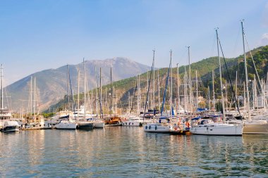 Şatafatlı yatlar gün batımında limana yanaştı. Limandaki büyük yatların göz kamaştırıcı manzarası. Dağların arkaplanı.