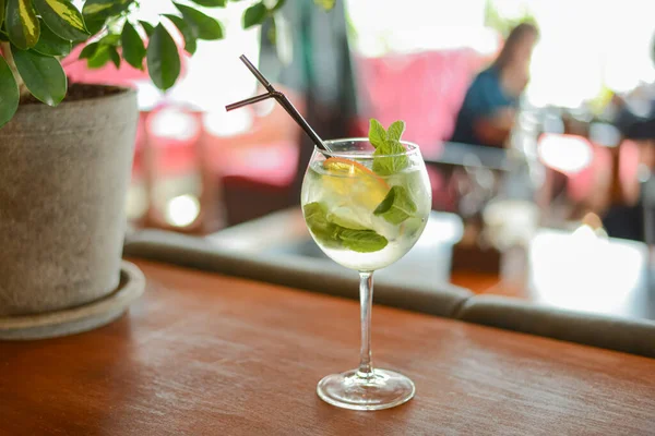 Cóctel de alcohol frío de verano con hielo y naranja en un vaso alto sobre una mesa de madera sobre fondo borroso del restaurante . — Foto de Stock