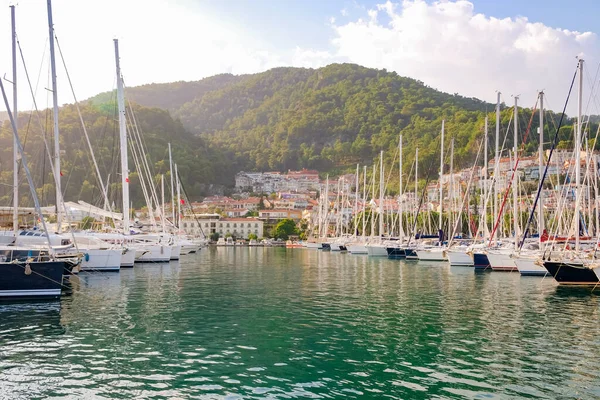 Luxury yachts docked in sea port at sunset. A stunning view of mega yachts in the port. Mountains background.