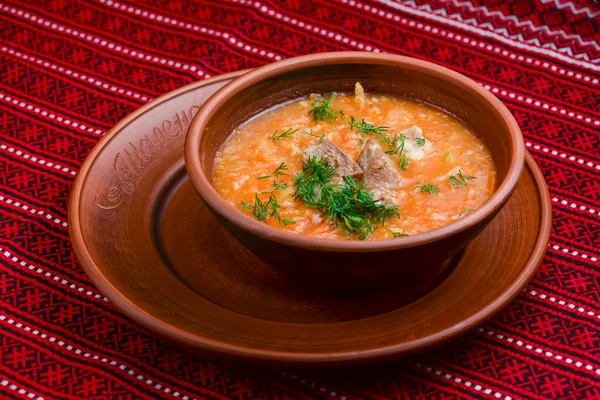 Куриный суп с овощами и мясом подается в белой миске на деревенском деревянном фоне с красной клетчатой скатертью . — стоковое фото