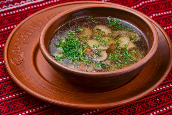 Курячий суп з овочами та м'ясом подається в білій мисці над сільським дерев'яним тлом з червоною пляшкою . — стокове фото