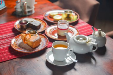 Tatlı tatlılı çay saati için masa hazır. Çikolatalı kek, vanilyalı kek, panna cotta. Çay demliği ve tatlı çay..