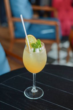 Buzlu ve portakallı soğuk yaz alkollü kokteyli ahşap masada, bulanık restoran arka planında uzun bir bardakta..