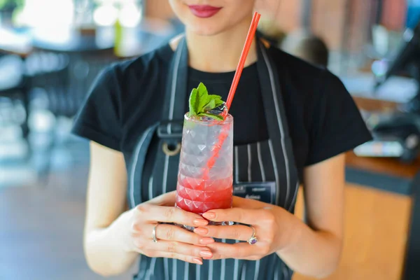 Attractive young woman waiter holding red colorful refreshing cocktail with ice and lime. Fruit tropical mix drink. — Stock Photo, Image