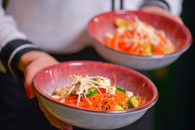Garson iki tabak sağlıklı yeşil salata servis ediyor. İki tabak peynirli sebze salatası..