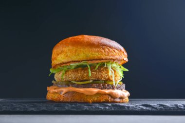 Siyah arka planda baharatlı lezzetli bir hamburgerci. Fast food, abur cubur kavramı.