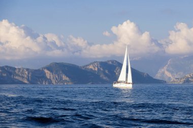 Mavi gökyüzü arka planında denizde yarış yatı. Huzurlu deniz manzarası. Seyahat konsepti, seyahat.