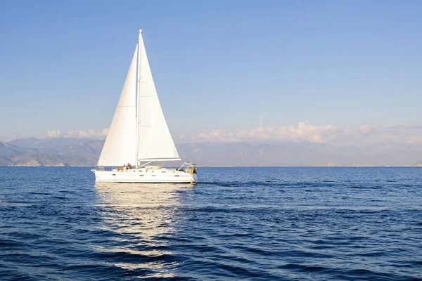 Mavi gökyüzü arka planında denizde yarış yatı. Huzurlu deniz manzarası. Seyahat konsepti, seyahat.
