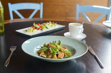 Siyah ahşap arka planda mavi bir tabakta taze sebzeli salata..