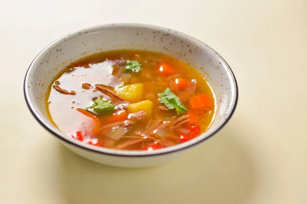 Deliciosa sopa de guiso con carne y verduras servidas en un tazón blanco sobre fondo amarillo pastel brillante. Dieta saludable . — Foto de Stock