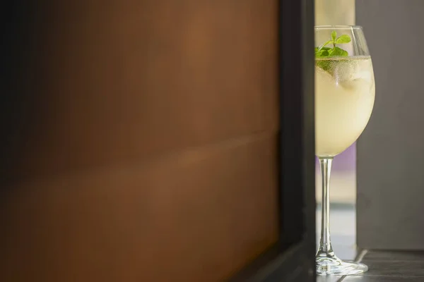 Cóctel de alcohol frío de verano con hielo y naranja en una copa de vino sobre fondo claro y borroso . — Foto de Stock