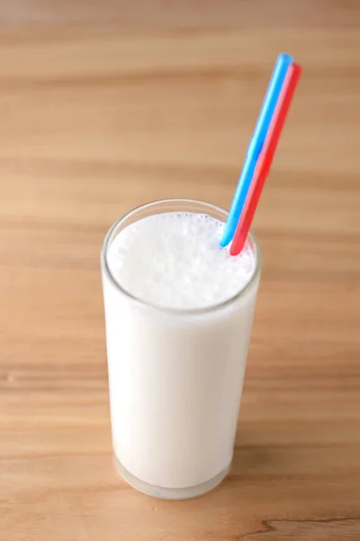 Vanilyalı milkshake, açık sade ahşap masa üzerinde iki plastik pipetle uzun bir galede.. — Stok fotoğraf