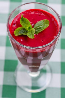 Yeşil ekose masa örtüsünde servis edilen tropikal bir içecek, böğürtlen ve nane kokteyli. Meyve suyu, taze meyve suyu..