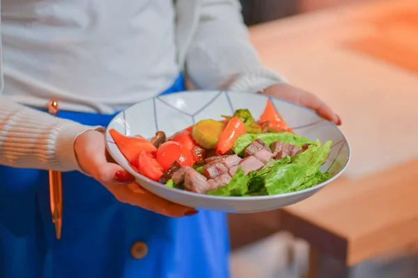 Garçom serve carne assada e salada de legumes com tomate e brocolli em uma tigela branca. Comer fora no restaurante . — Fotografia de Stock